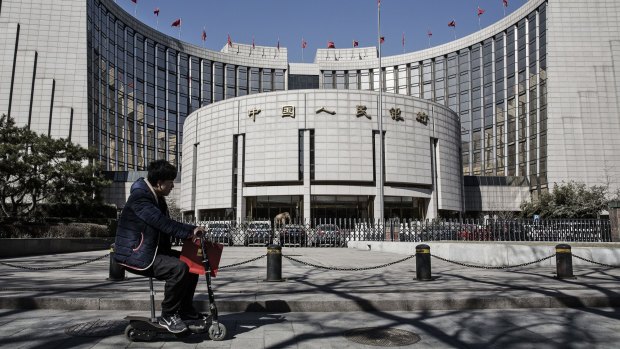 A man rides a scooter past the People's Bank of China headquarters in Beijing.