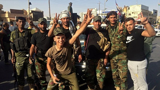 Iraqi security forces and volunteers celebrate in Kirkuk on Monday. 
