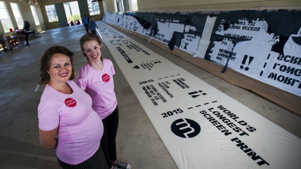 Megalo Print Studio and Gallery artistic director Ingeborg Hansen and programs manager Megan Hinton celebrate the studio's 35th birthday by creating the longest screen print of the studio's timeline.