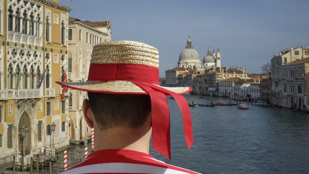 A gondolier surveys the Venice cityscape.