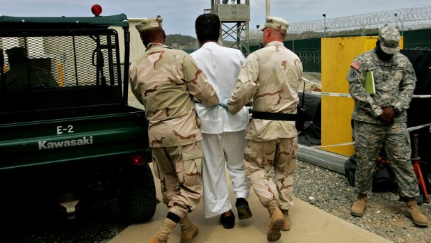 A Guantanamo detainee escorted by US military personnel on the grounds of the Guantanamo Bay naval base in 2007.