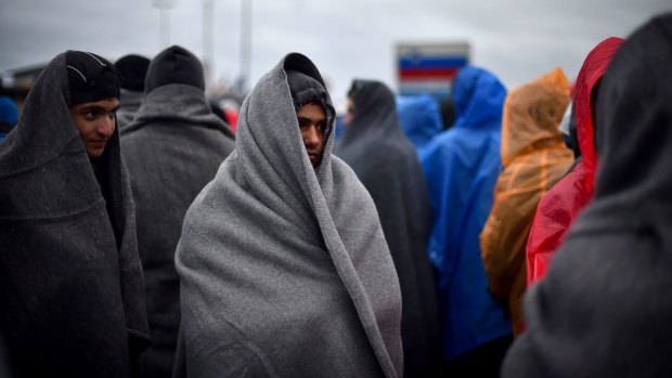 Refugees attempt to keep warm as they wait in the rain at the Trnovec border crossing.