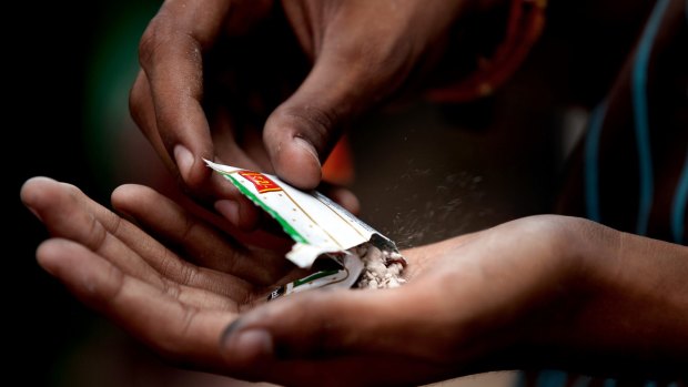 Dangerous habit: An Indian man opens a pouch of chewing tobacco.