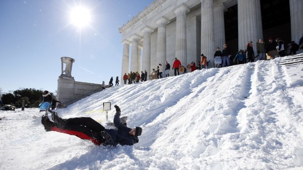The sun emerges ... A man bounces at the bottom as he sleds down the snow-covered steps of the Lincoln Memorial in Washington. Millions of Americans began digging out on Sunday following a mammoth blizzard that hit the East Coast.