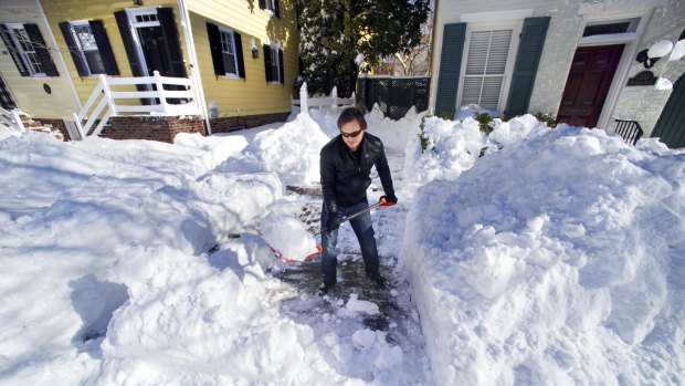 Maok Niebaur, 25, shovels snow for an elderly neighbour in Alexandria, Virginia on Sunday. Millions of Americans are digging their cars out and clearing driveways and paths on Monday.