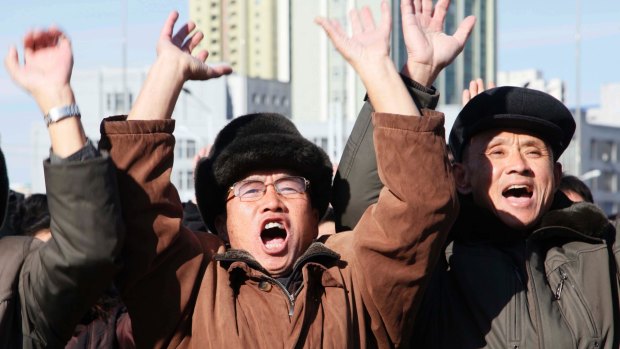 People cheer as they watch the news broadcast announcing North Korean leader Kim Jong-un's order to test-fire a Hwasong-15 missile.