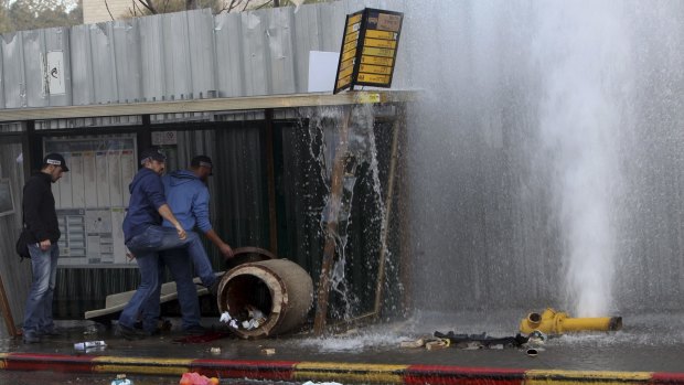 Israeli policemen push a trash container, as water sprays from a burst fire hydrant, at a scene of the car ramming in Jerusalem on Monday.