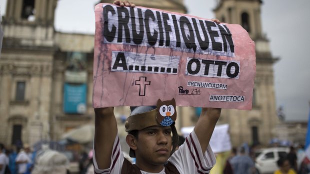 A demonstrator wearing a Roman soldier costume holds up a sign that reads in Spanish: 'Crucify Otto' outside the Metropolitan Cathedral during a national strike in Guatemala City.