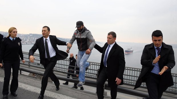Turkish President Recep Tayyip Erdogan's bodyguards escort Vezir Cakras, centre, towards Mr Erdogan's car after they convinced him not to jump from the Bosphorus Bridge in Istanbul on Friday.