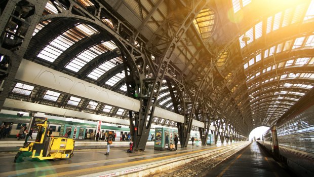 Train platforms under the cast iron and glass vaults of Milano Centrale railway station in Italy.