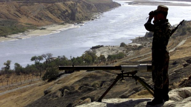 A Russian border guard observes the Afghan territory over the Pyandzh River, controlled by the Afghanistan's Taliban rulers, in 2001.