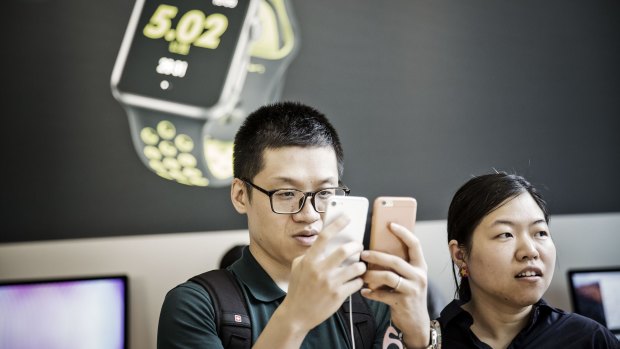 A customer inspects iPhone 7 models in a Shanghai shopping mall.