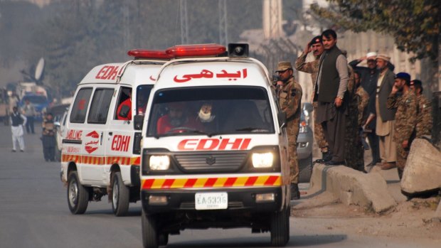 Ambulances leave a military-run school where Taliban gunmen have taken hostages.