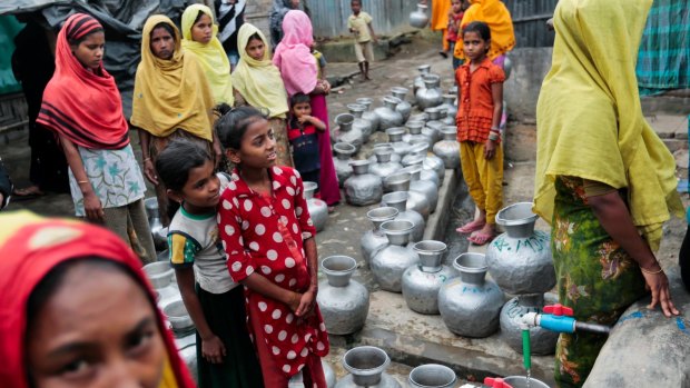 Rohingya women and children wait in a queue to collect water at the Leda camp, an unregistered camp for Rohingya in Teknaf, 296 kilometers south of Dhaka, Bangladesh.