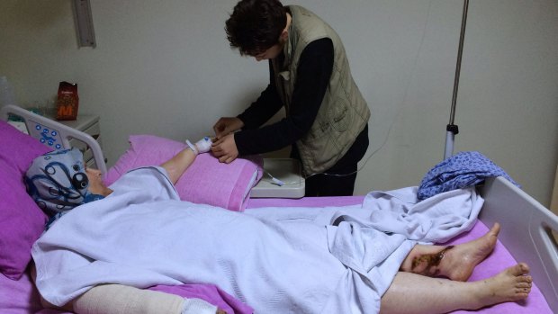Abdulhamid Khanfoura, 16, helps his wounded mother Zahra Khanfoura, 48, who was burned by a Russian airstrike that hit her house in the central Syrian village of Habeet.