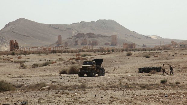 Residents walk near a military truck that belongs to forces loyal to Syria's President Bashar al-Assad, near the historical city of Palmyra on Tuesday. 