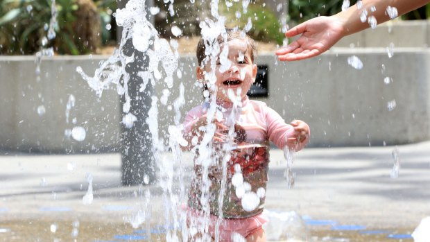 Anika, 2, plays in the water feature in Tumbalong Park, Darling Harbour.