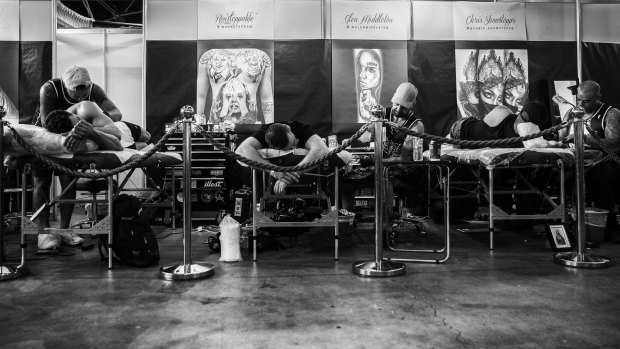 Tattoo artists working on clients at the event.  
