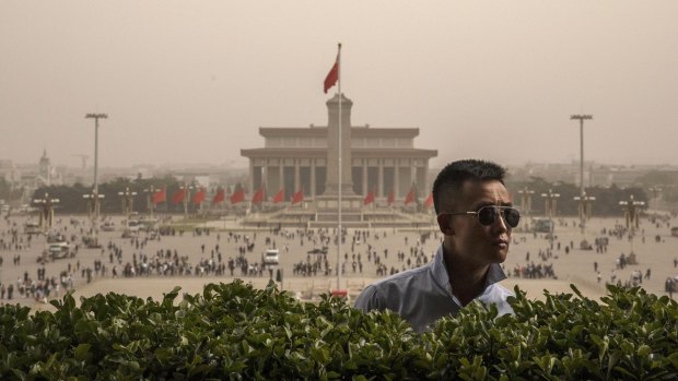 A Chinese police officer stands guard during a sandstorm overlooking Tiananmen Square.