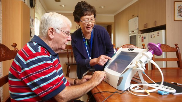 Telehealth nurse Lay Jean Woo shows patient Jack Fernihough how to use a home-monitoring system.