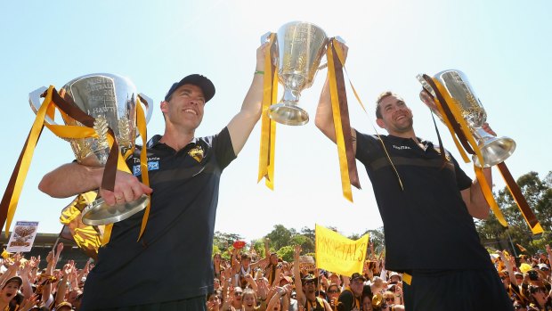 Alastair Clarkson the coach and Luke Hodge the captain of the Hawks pose with the 2013, 2014 and 2015 premiership trophies during the Hawthorn Hawks AFL Grand Final fan day.