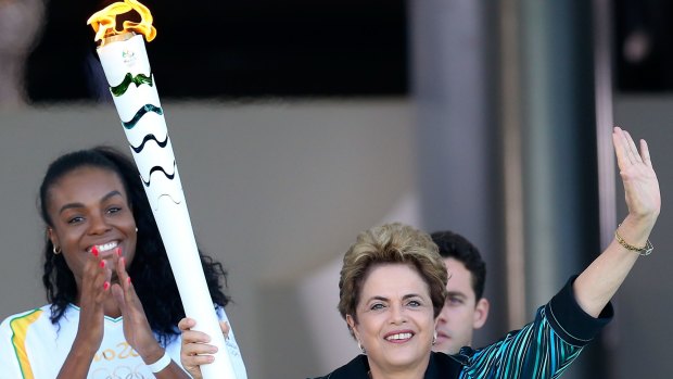 Suspended Brazilian President Dilma Rousseff hands the Olympic torch to the first torch bearer Brazilian volleyball player Fabiana Claudino on the ramp of the Palacio do Planalto, in Brasilia, in May.