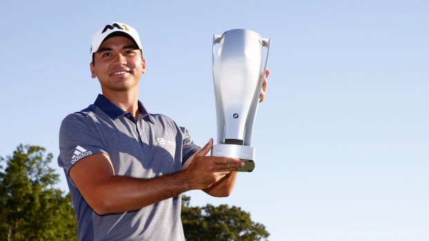 Jason Day celebrates with the winner's trophy.