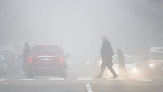 Pedestrians make their way through the fog in Canberra.