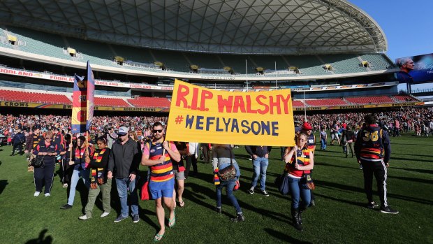 Crows supporters carry a sign at Adelaide Oval in memory of the late Phil Walsh.