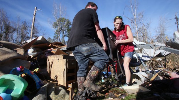 Clint Lowery, left, and Amanda Lowery, right, remove a deep fryer from the family's tornado damaged mobile home in Century, Florida on February 16.