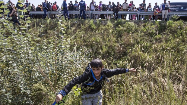 A boy flees a collection point set up to transport refugees to camps in Morahalom, Hungary. 