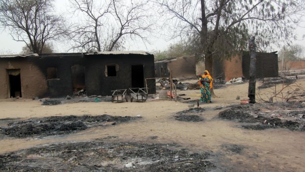 A woman walks past burnt houses in Baga in 2013 after a clash between officers of the Joint Task Force and Boko Haram members. 