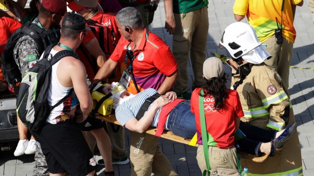 An injured woman is taken away after being struck by an overhead television camera that fell from wires suspending it over Olympic Park in Rio on Monday.