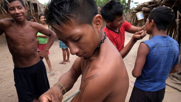 Young men apply ink to their skin in Awa Village.
