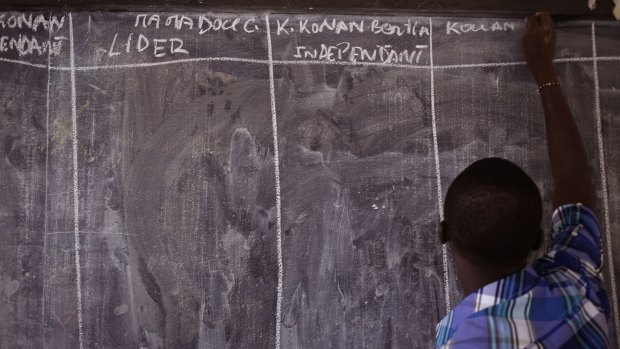 A election official writes each candidate's name on a chalk board before vote counting started in Abidjan, Ivory Coast on Sunday.