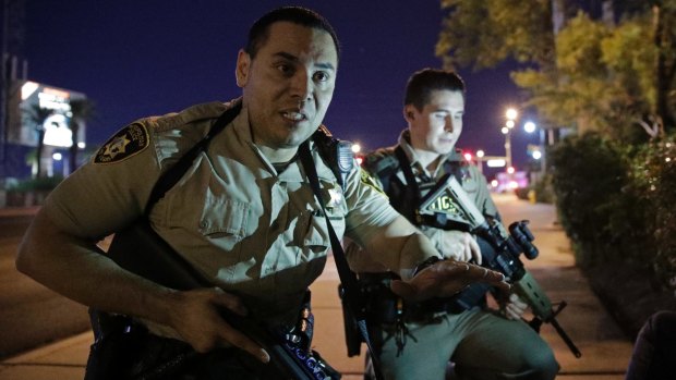 Police officers tell people to take cover after shootings in Las Vegas.