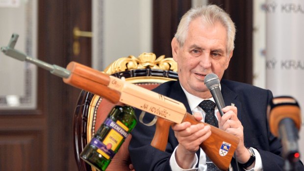 Czech President Milos Zeman holds a mock submachine gun inscribed with the words "At journalists", and a bottle of Becherovka liquor instead of the gunstock, in October last year. 