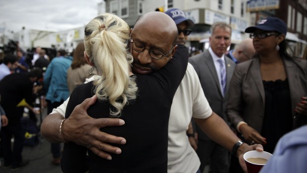 Philadelphia Mayor Michael Nutter, centre right, hugs Lori Dee Patterson, a nearby resident, after she handed him a cup of coffee after he spoke at a news conference.