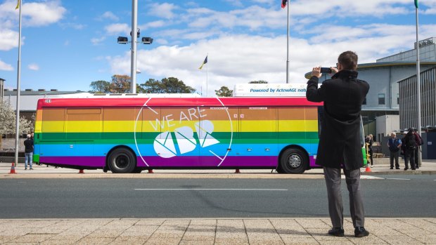 Minster for Road Safety Shane Rattenbury takes a photo of a bus newly painted in rainbow colours in support of marriage equality on Tuesday. 