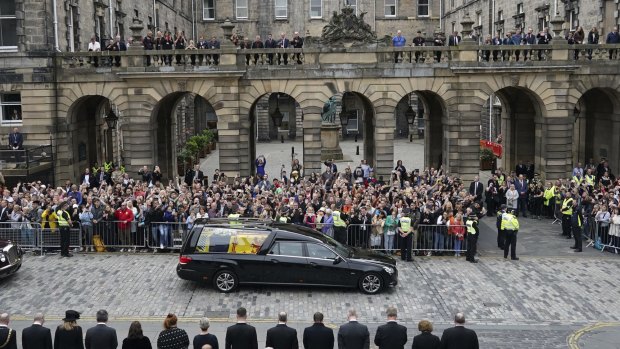 Crowds watch as the hearse carrying the coffin of Queen Elizabeth II passes Mercat Cross in Edinburgh.