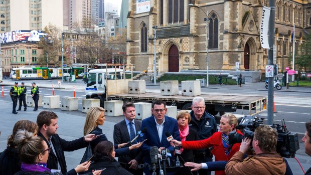 Premier Daniel Andrews speaks to the media as concrete bollards are installed at Federation Square in June.