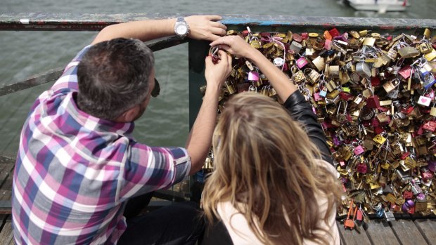 A couple place their padlock on the Pont des Arts in Paris last Friday. 