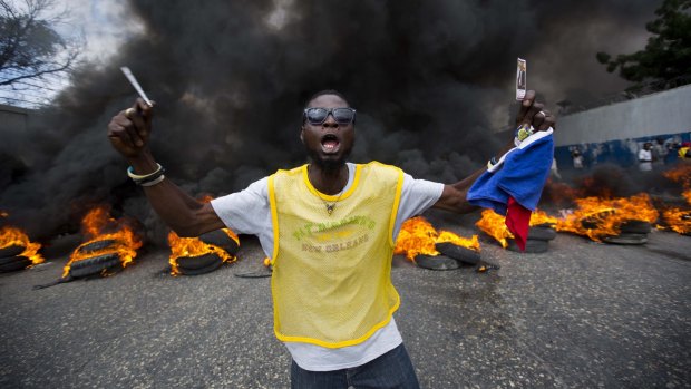 An anti-government demonstrator holds up a picture of former president Jean Bertrand Aristide as he demands the president's resignation in Port-au-Prince on Saturday.