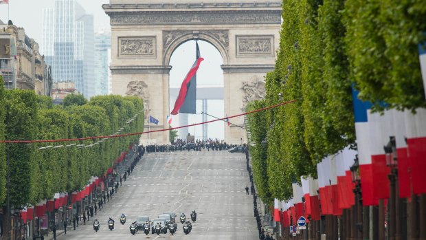 The motorcade of Emmanuel Macron and Francois Hollande drives down the Champs Elysees  after attending the ceremony to mark Western allies' World War Two victory.