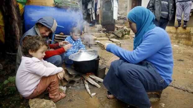 A Syrian refugee prepares food with her children in Lebanon in 2013.