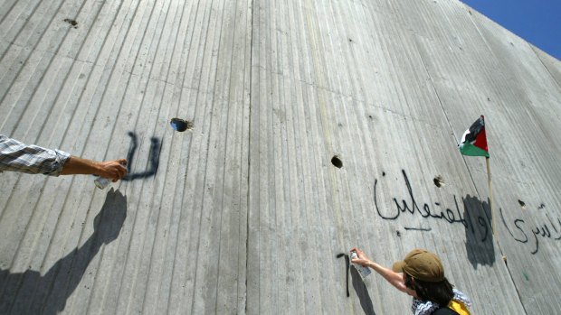 Foreign activists spray graffiti on the wall erected by Israel near the northern West Bank town of Qalqilya, which is also walled off on three sides.