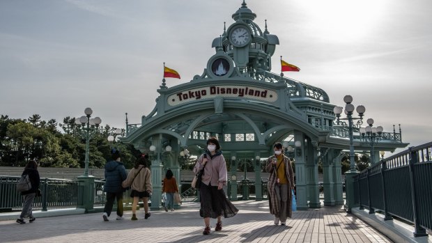 People pass beneath an archway leading to Tokyo Disneyland on the day it announced it will close.
