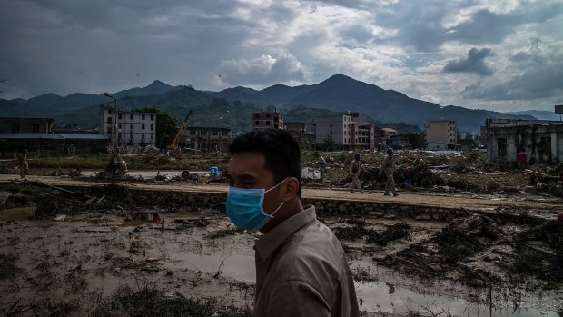 A man stands in front of the damaged village at Bandong Town.