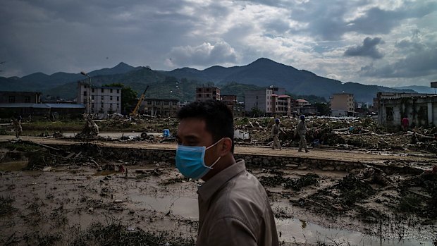 A man stands in front of the damaged village at Bandong Town.