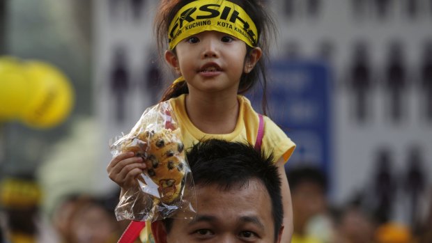A supporter of pro-democracy group Bersih carries a child on his shoulders during Sunday's protest in Kuala Lumpur.
